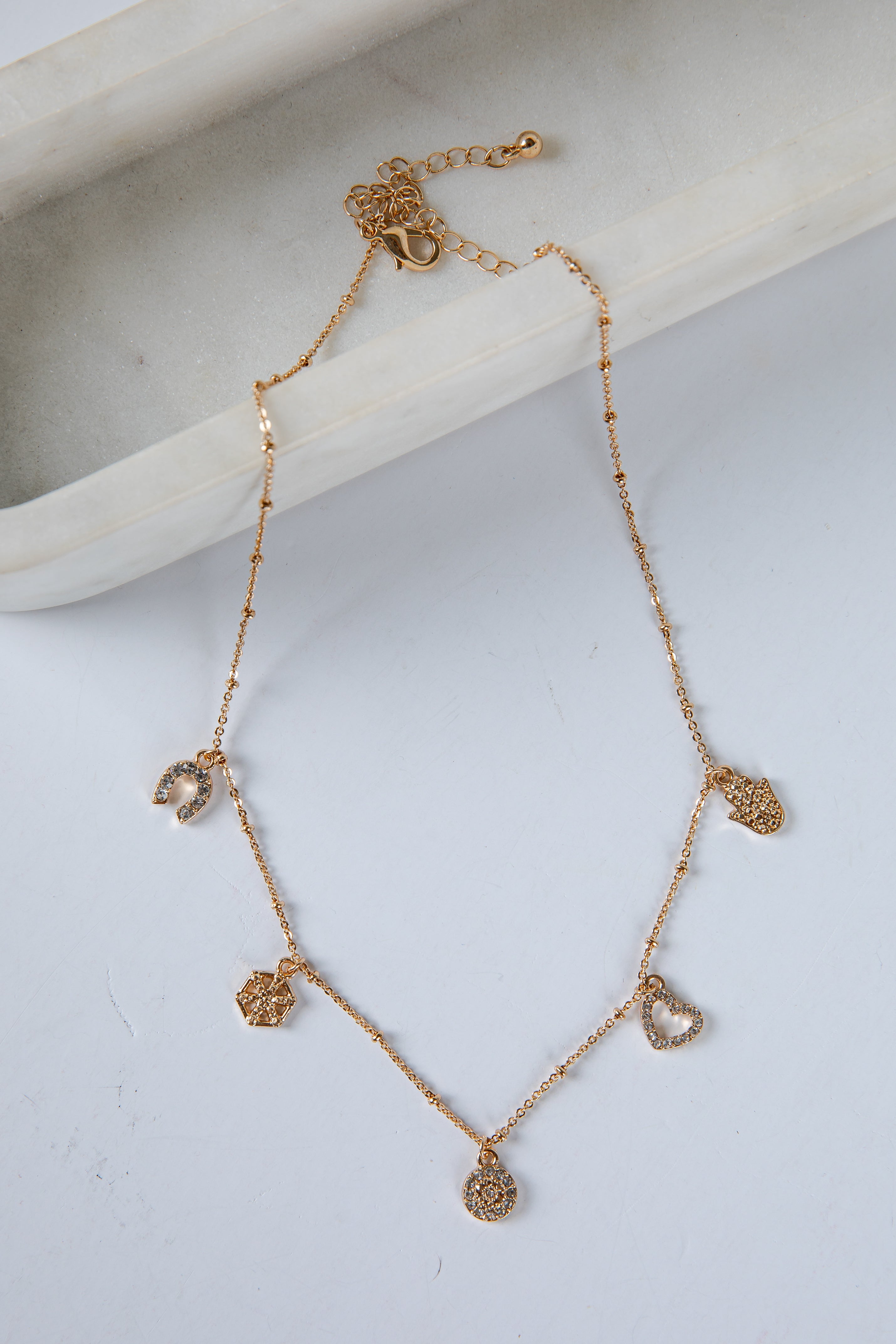 Gold necklace with heart-shaped pendants on a light gray surface