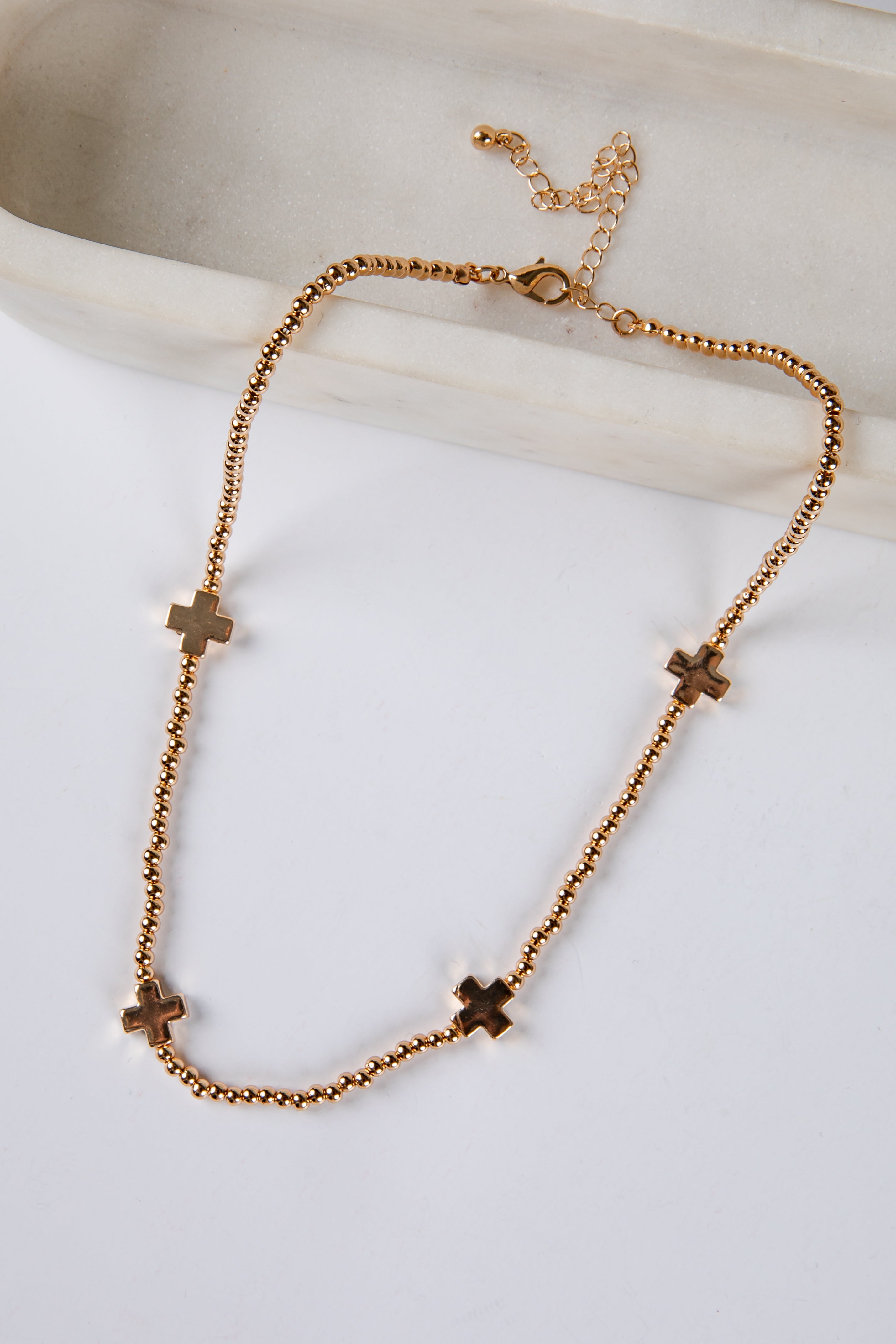 Gold necklace with cross pendants on a light background
