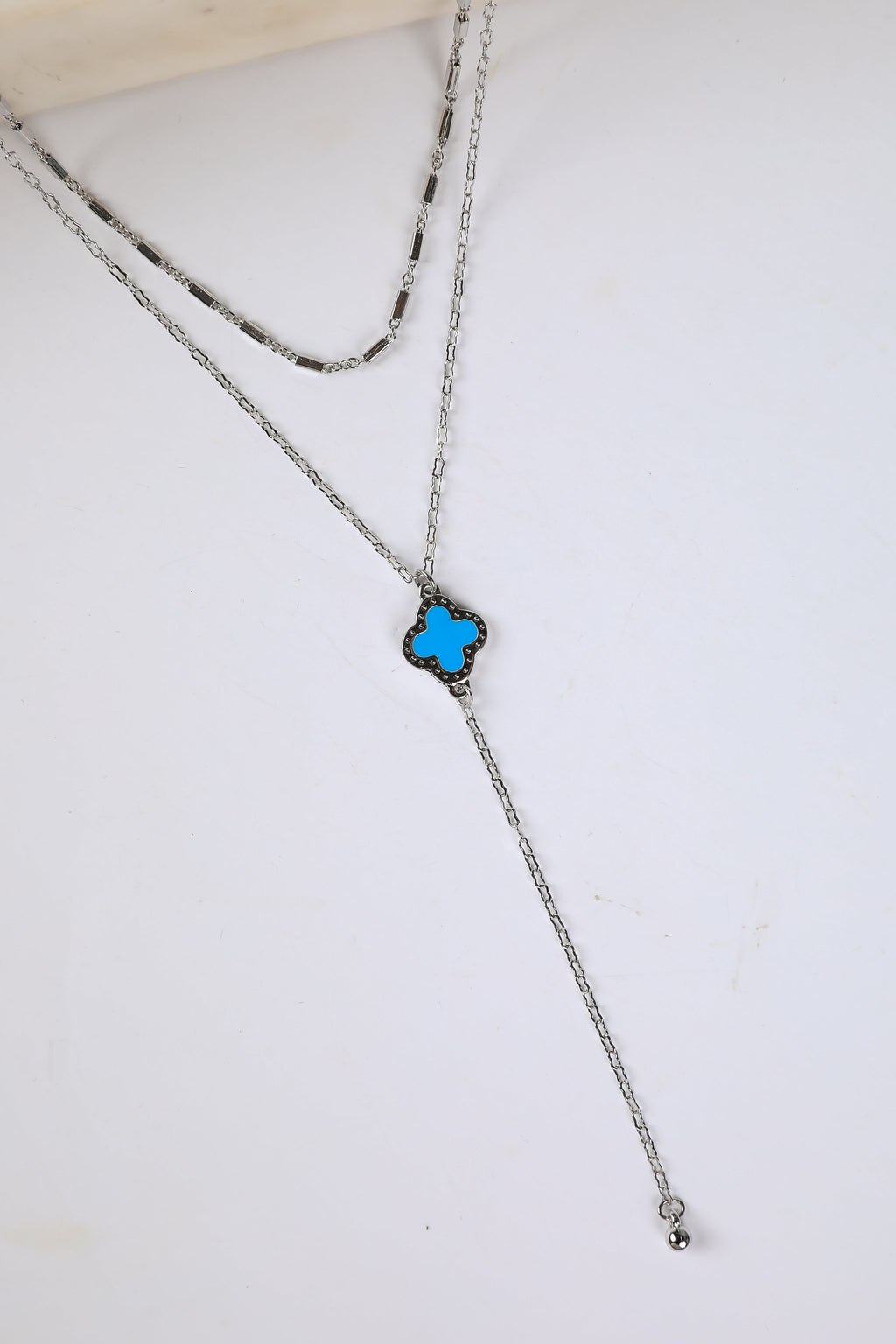Necklace with a blue flower pendant on a white surface
